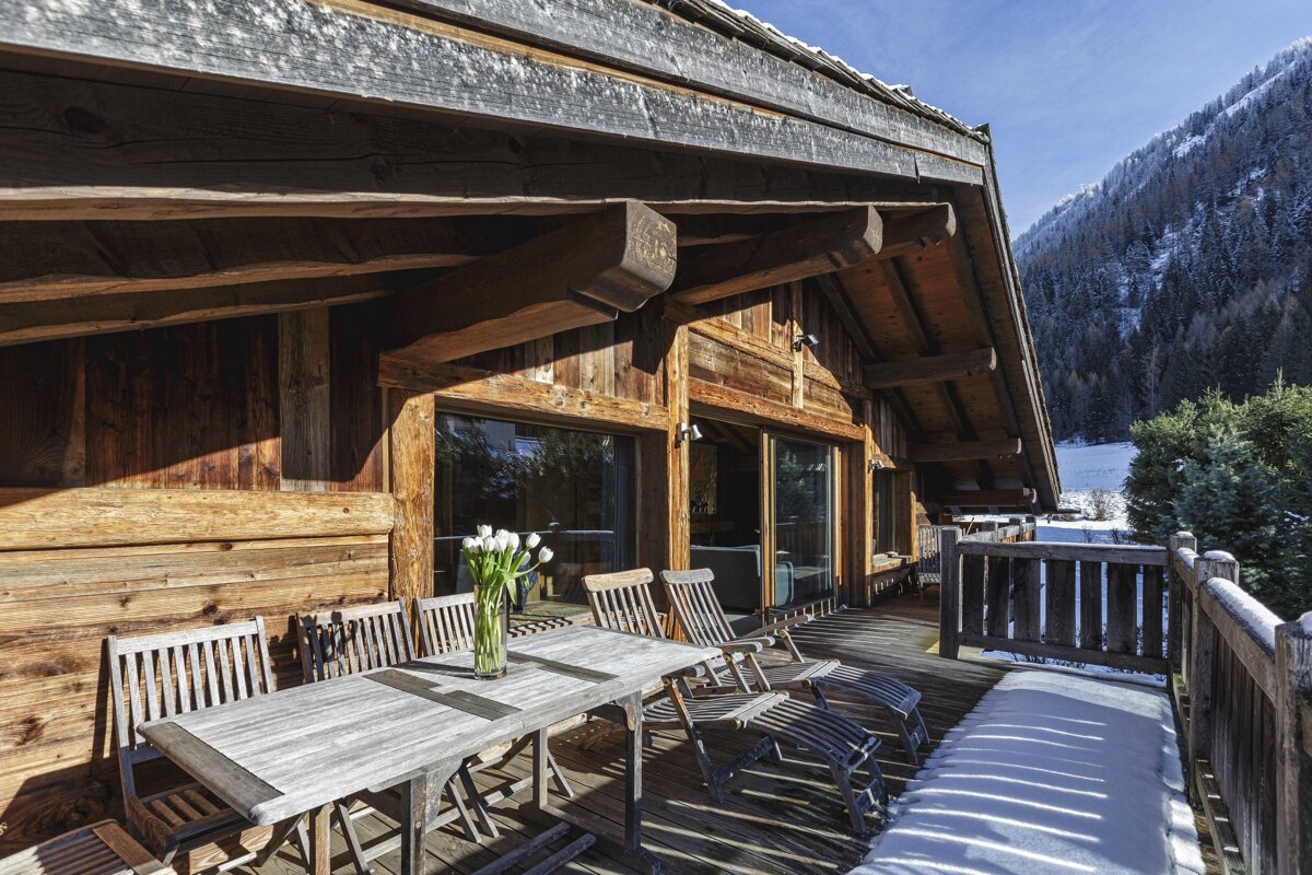 A wooden deck with a table and chairs and a vase of flowers