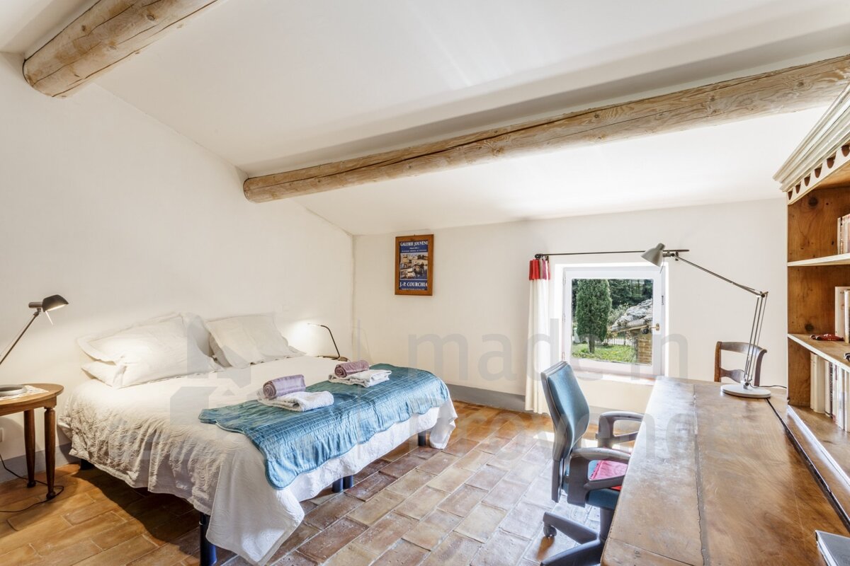 A bedroom with a bed a desk and a picture on the wall