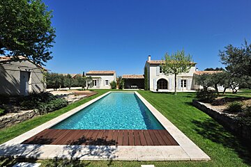 A house with a large swimming pool in front of it