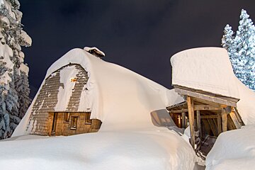 A snowy house with a roof that is covered in snow