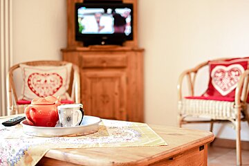 A teapot sits on a table in front of a television