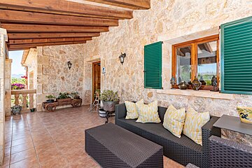 A patio with a couch and a table with green shutters