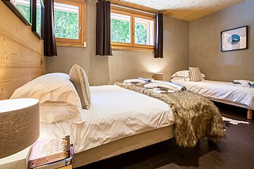 A bedroom with two beds and a stack of books on the bedside table