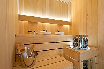 A harvia bucket sits on a wooden bench in a sauna