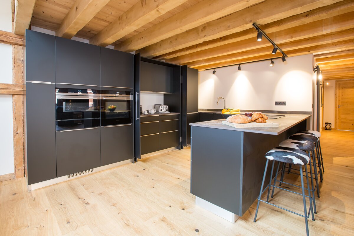 A kitchen with black cabinets and wooden beams