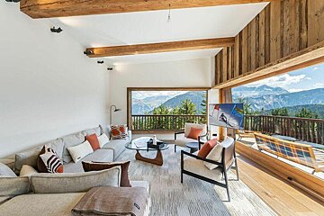 A living room with a couch and chairs and mountains in the background