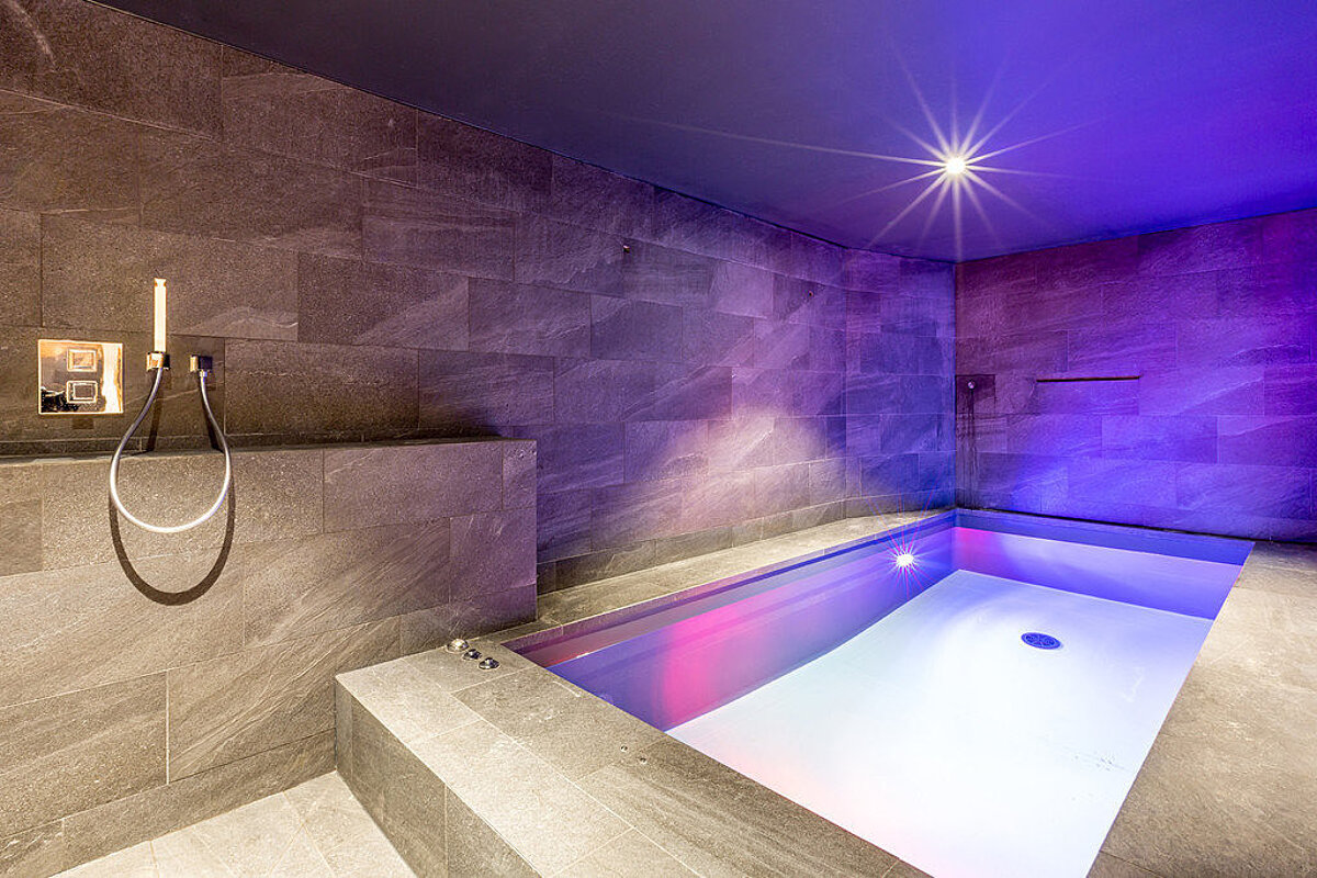 A bathtub in a bathroom with purple and pink lights