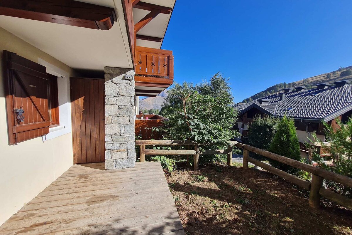 A wooden walkway leading to a balcony with mountains in the background
