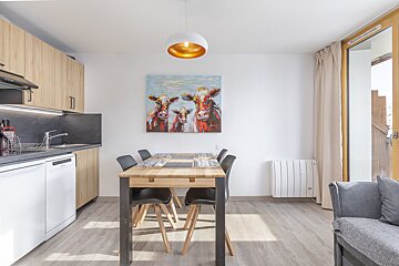 A kitchen with a table and chairs and a painting of cows on the wall