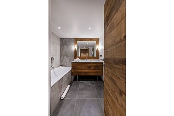 A bathroom with a bathtub and a wooden vanity