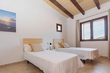 A bedroom with two beds and a painting on the wall