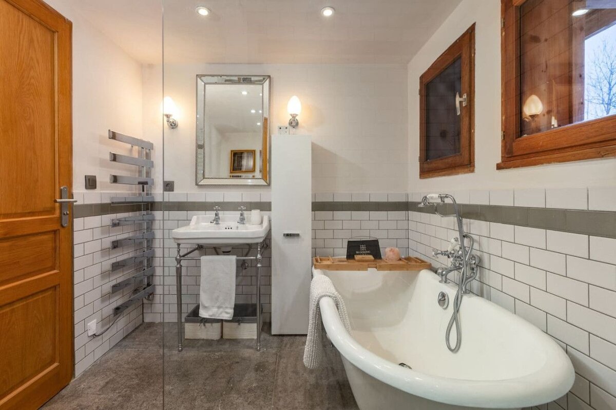 A bathroom with white tiles and a bathtub