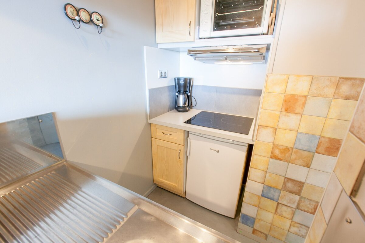 A small kitchen with a stove top oven and a fridge
