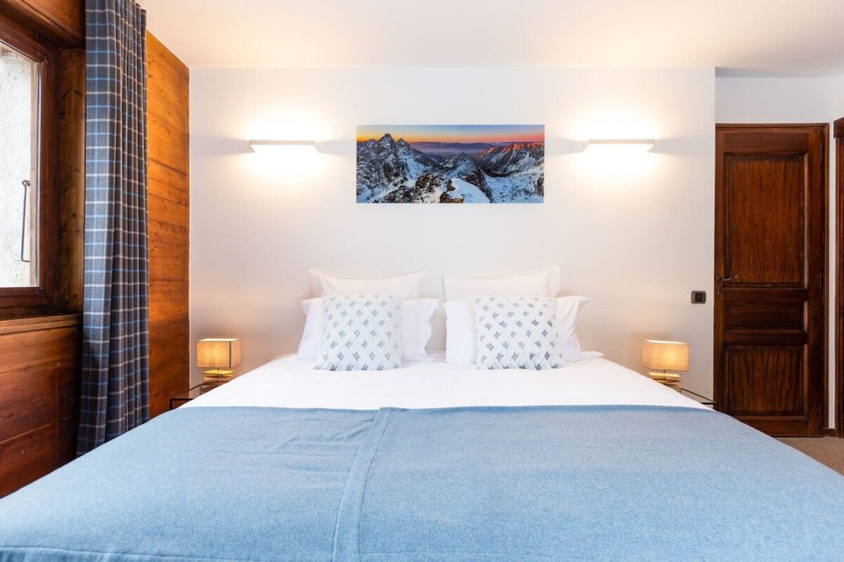 A bedroom with a painting on the wall above the bed