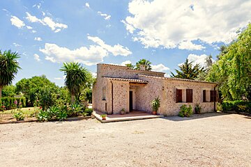 A stone house with a lot of plants in front of it