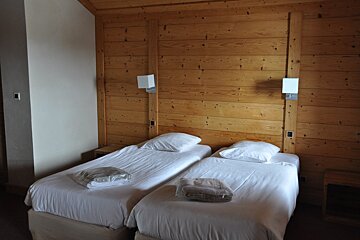 A bedroom with two beds and a wooden wall