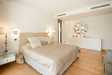 A bedroom with a large bed and a mirror on the wall