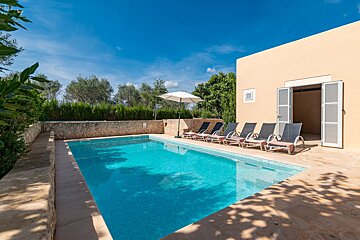 A swimming pool with chairs and an umbrella in front of a house