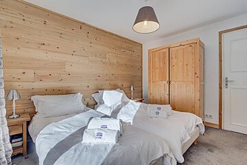 A bedroom with a wooden wall and two beds