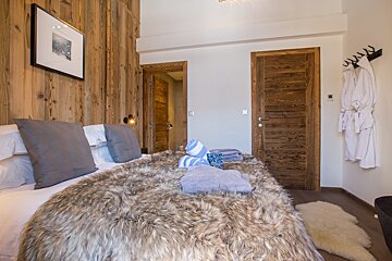 A bed with a fur blanket and pillows in a bedroom