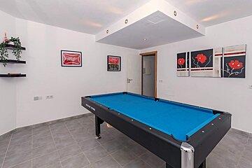 A pool table in a room with a coca cola poster on the wall