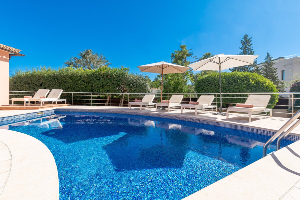 A swimming pool with chairs and umbrellas around it