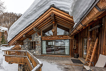 A wooden house with snow on the roof