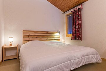 A bedroom with a bed a nightstand and a lamp