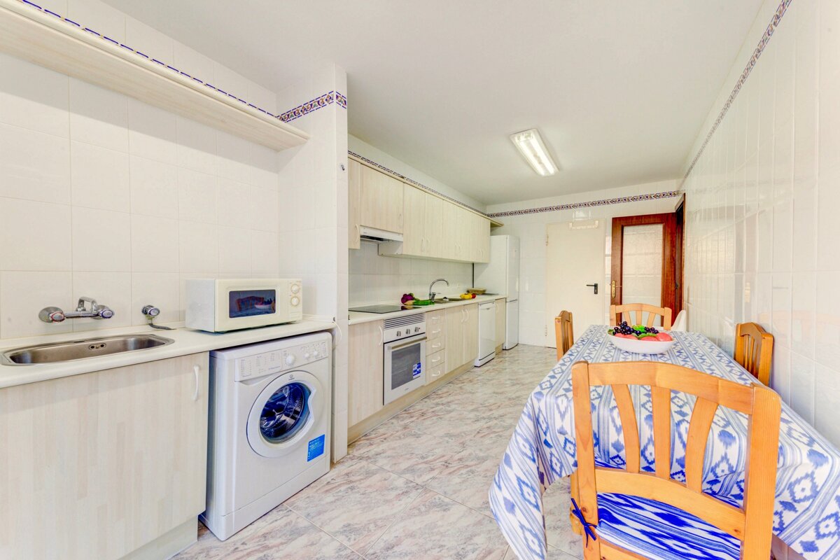 A kitchen with a washing machine and a microwave