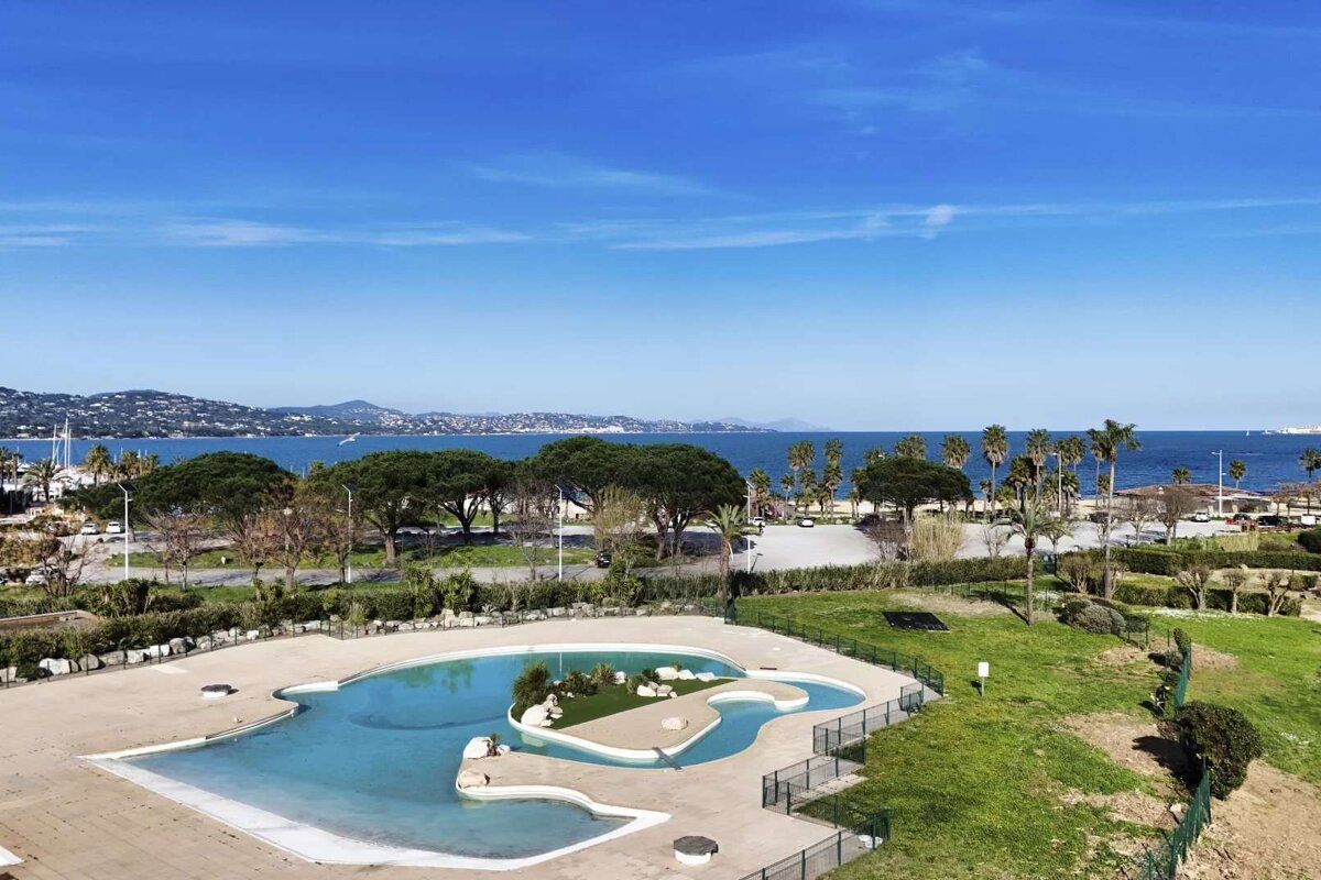 A large swimming pool surrounded by a fence with a view of the ocean