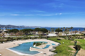 A large swimming pool surrounded by a fence with a view of the ocean