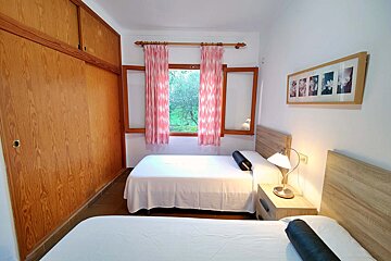 A bedroom with two beds and a window with pink curtains
