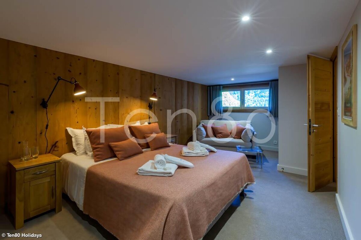 A bedroom with a bed and a chair and the word ten80 on the wall