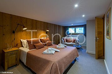 A bedroom with a bed and a chair and the word ten80 on the wall