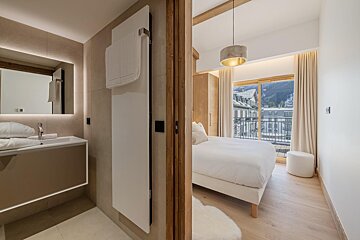A bathroom next to a bedroom with a large window