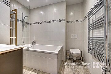 A bathroom with a bathtub toilet and a towel rack that says mountain base
