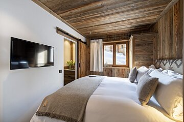 A bedroom with a large bed and a flat screen tv