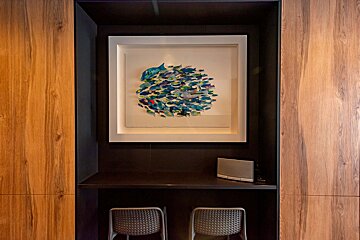A framed picture of fish hangs above two chairs