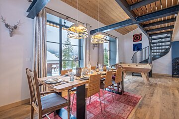 A dining room with a table and chairs and a spiral staircase