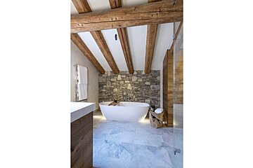 A bathroom with a stone wall and wooden beams
