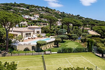 An aerial view of a large house with a tennis court in front of it