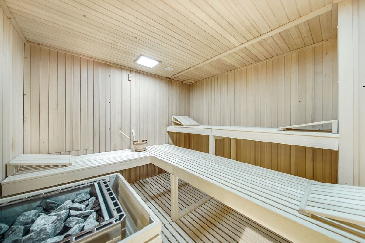 A sauna with wooden benches and a bucket of rocks
