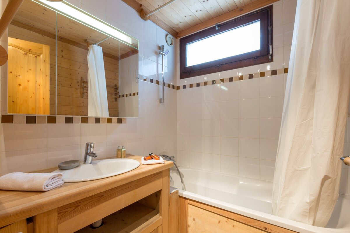 A bedroom with a bathtub and a wooden cabinet