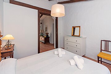 A bedroom with a white dresser and a mirror