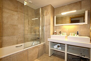 A bathroom with two sinks and a bathtub and a sign that says penta design