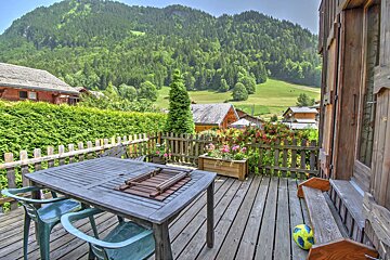 A table and chairs on a deck with a mountain in the background