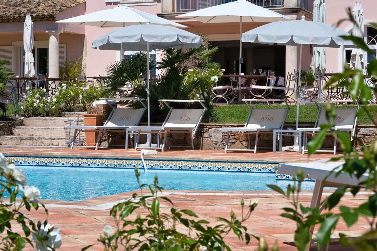 A swimming pool surrounded by chairs and umbrellas with the letter g on them