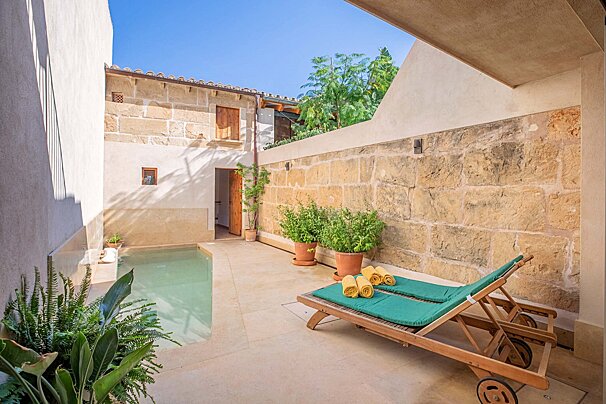 A patio with two lounge chairs and a swimming pool