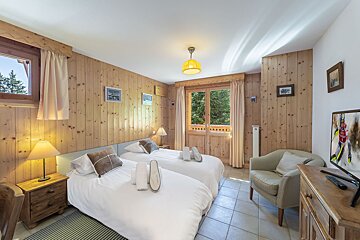 A bedroom with two beds a chair and a television