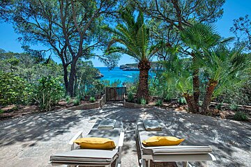 Two lounge chairs sit on a patio overlooking the ocean